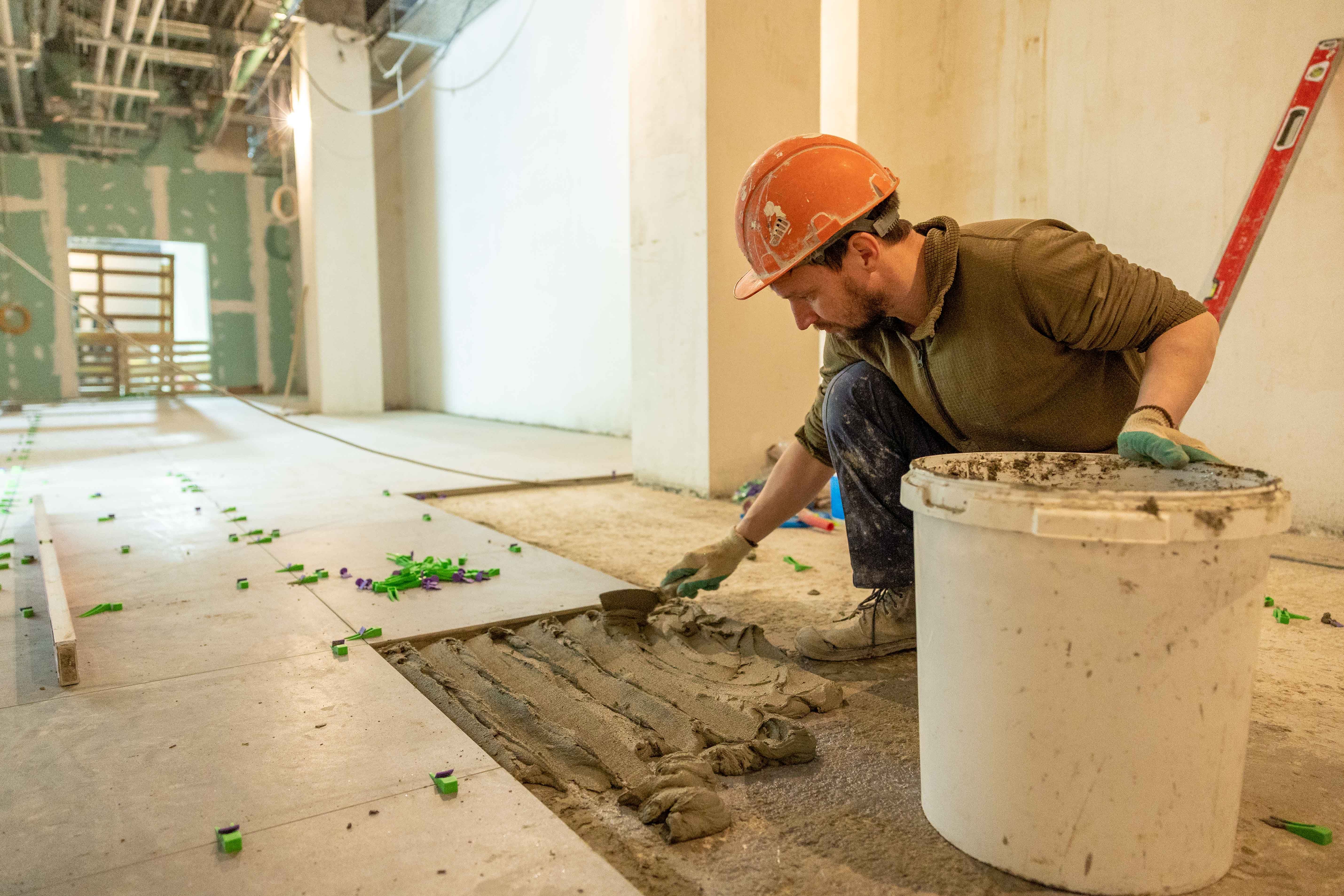 A flooring contractor installing hardwood flooring in a home.